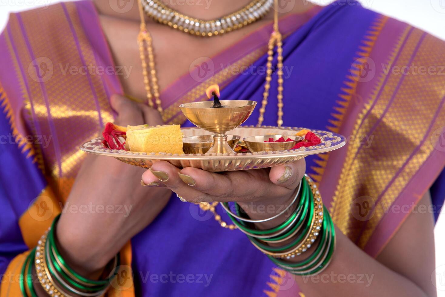 Indian woman performing worship, portrait of a beautiful young lady with pooja thali isolated on white background photo