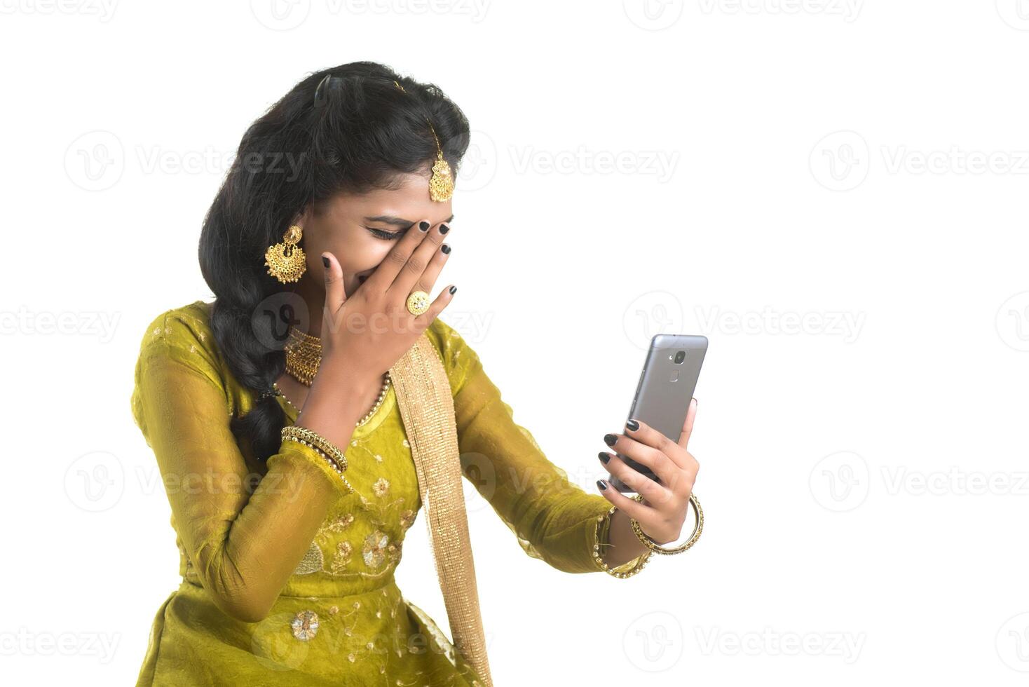 Young Indian traditional girl using a mobile phone or smartphone isolated on a white background photo