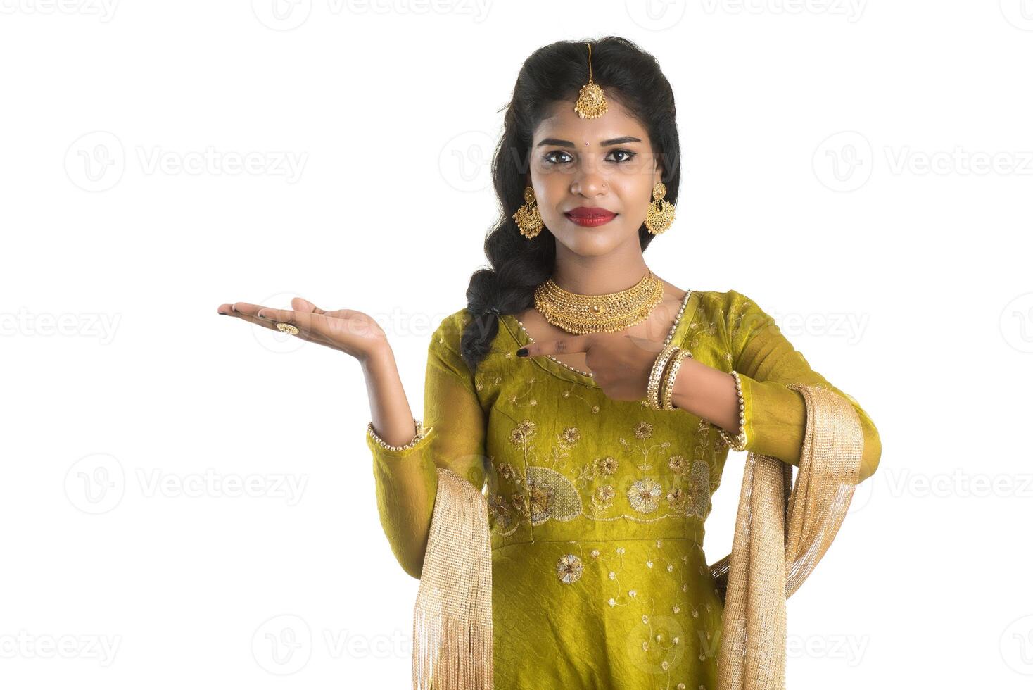 Portrait of cheerful Indian traditional young woman presenting something, showing copy space on her palm on a white background photo