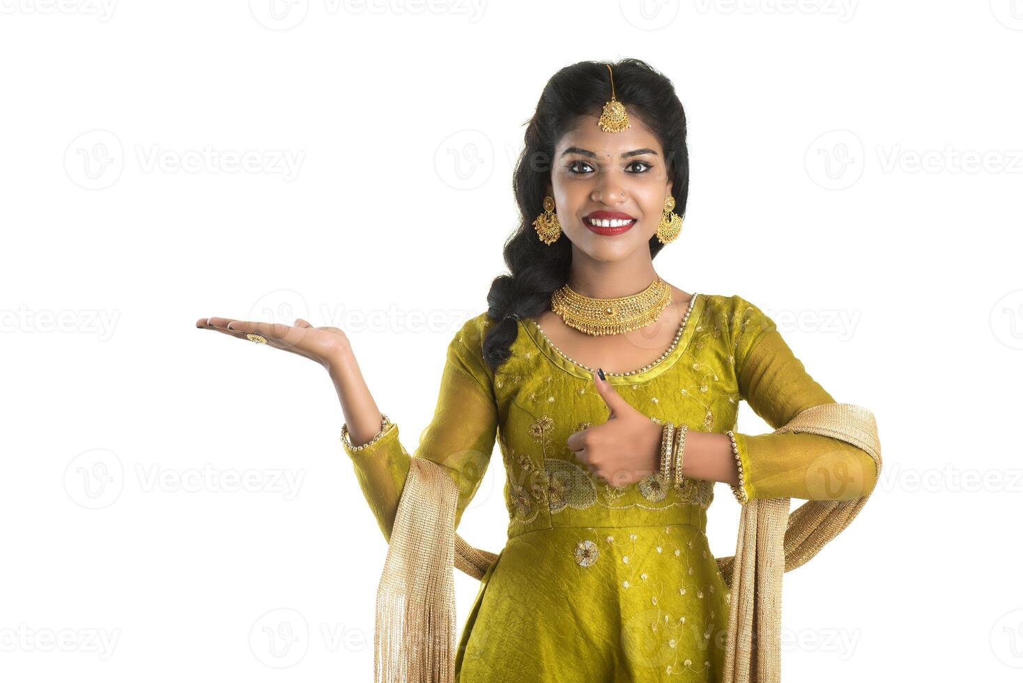 Portrait of cheerful Indian traditional young woman presenting something, showing copy space on her palm on a white background photo