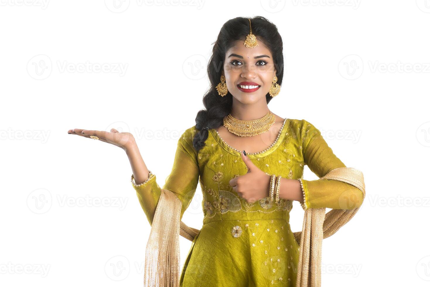 Portrait of cheerful Indian traditional young woman presenting something, showing copy space on her palm on a white background photo