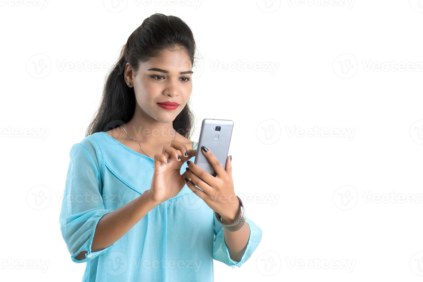 Young Indian girl using a mobile phone or smartphone isolated on a white background photo