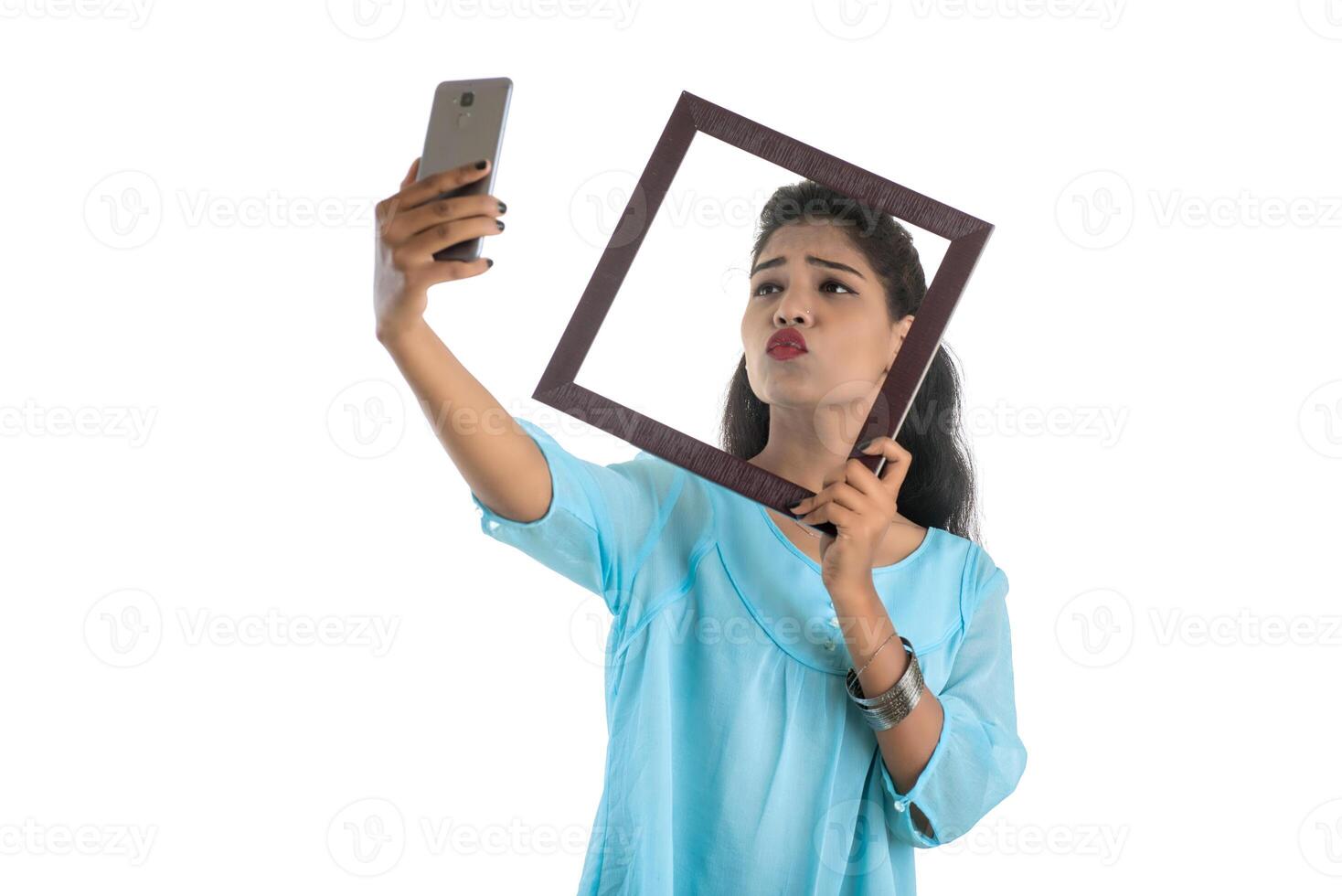 Young Indian girl using a mobile phone or smartphone with photo frame on a white background