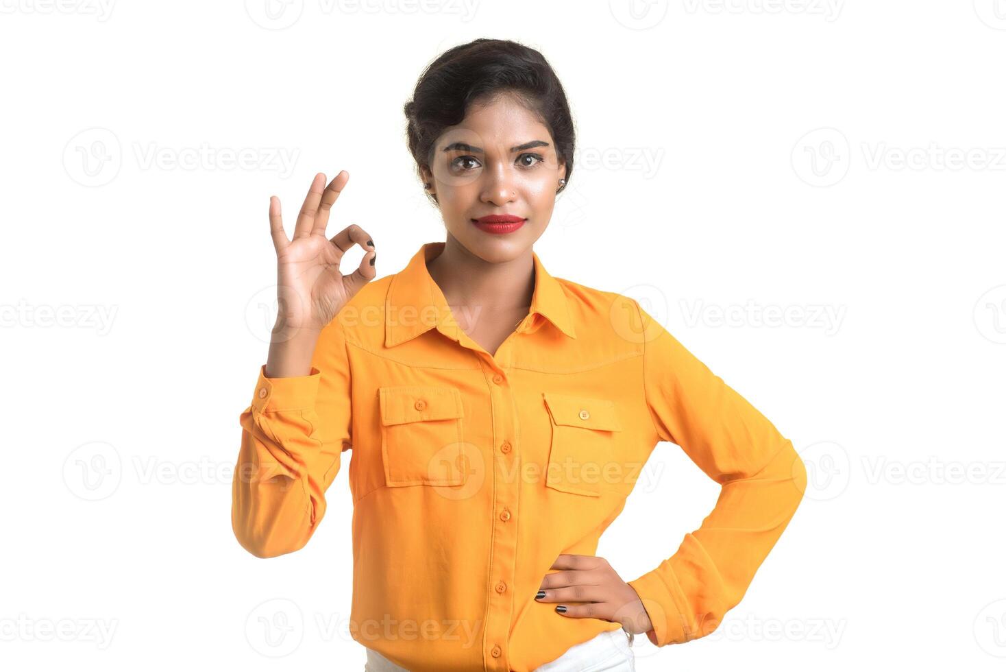 Smiling cheerful girl showing sign isolated on white background photo
