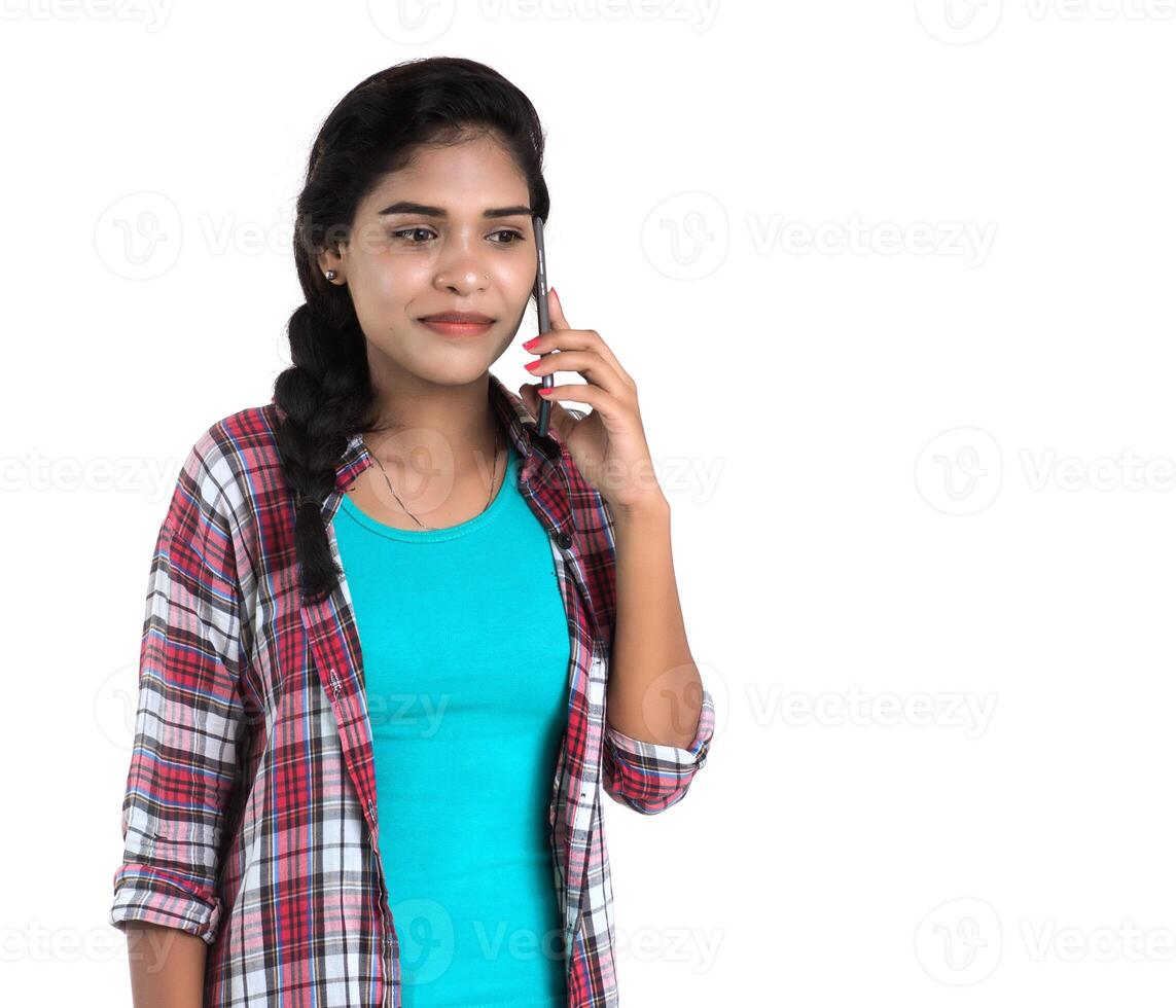 Young Indian girl using a mobile phone or smartphone isolated on a white background photo