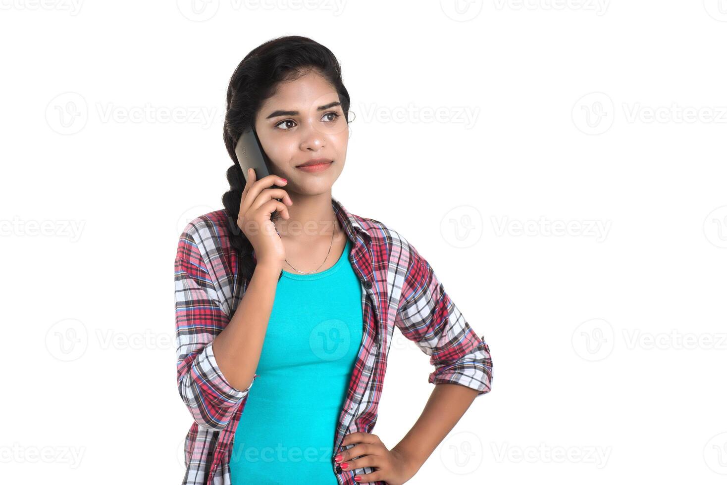 Young Indian girl using a mobile phone or smartphone isolated on a white background photo