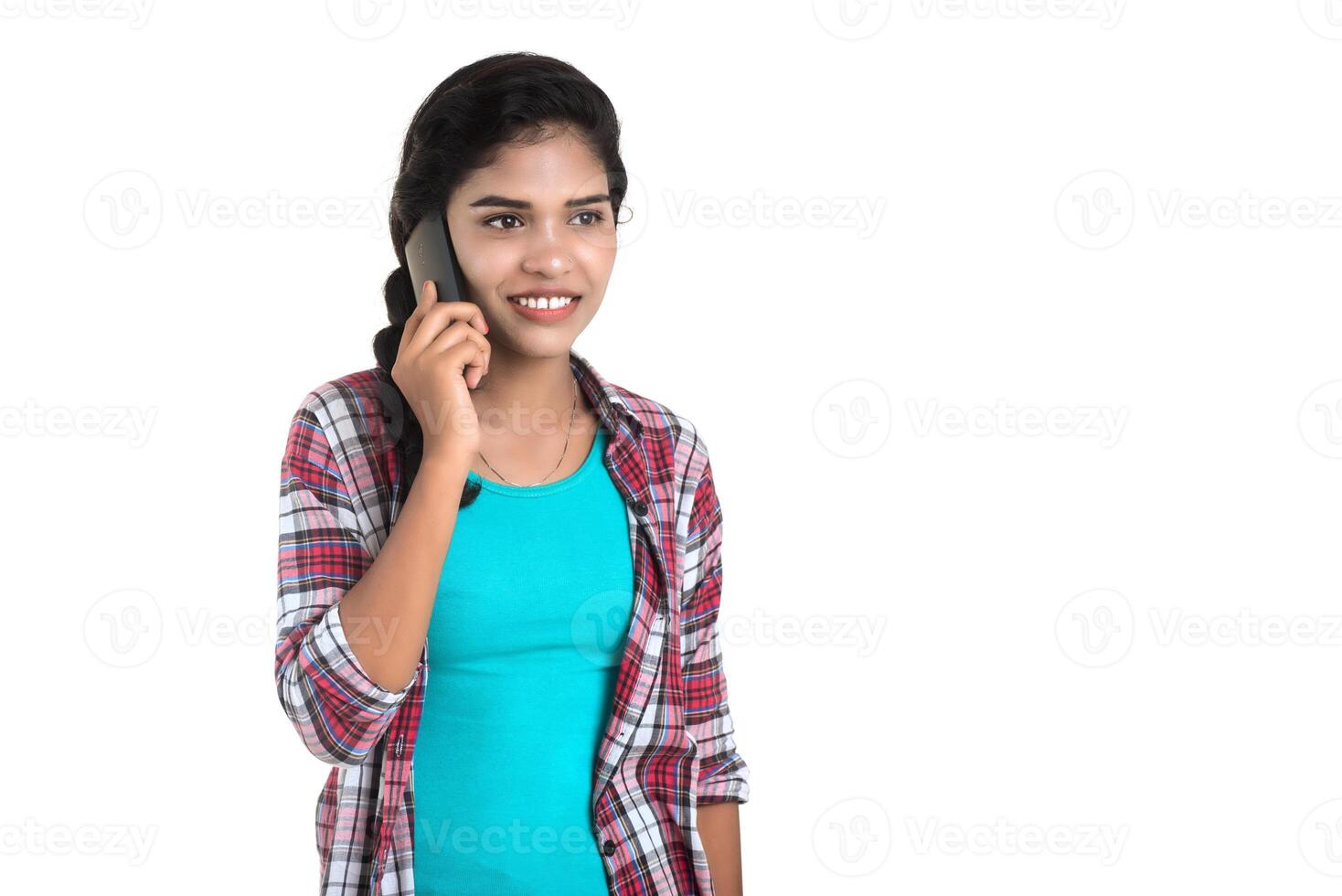 Young Indian girl using a mobile phone or smartphone isolated on a white background photo