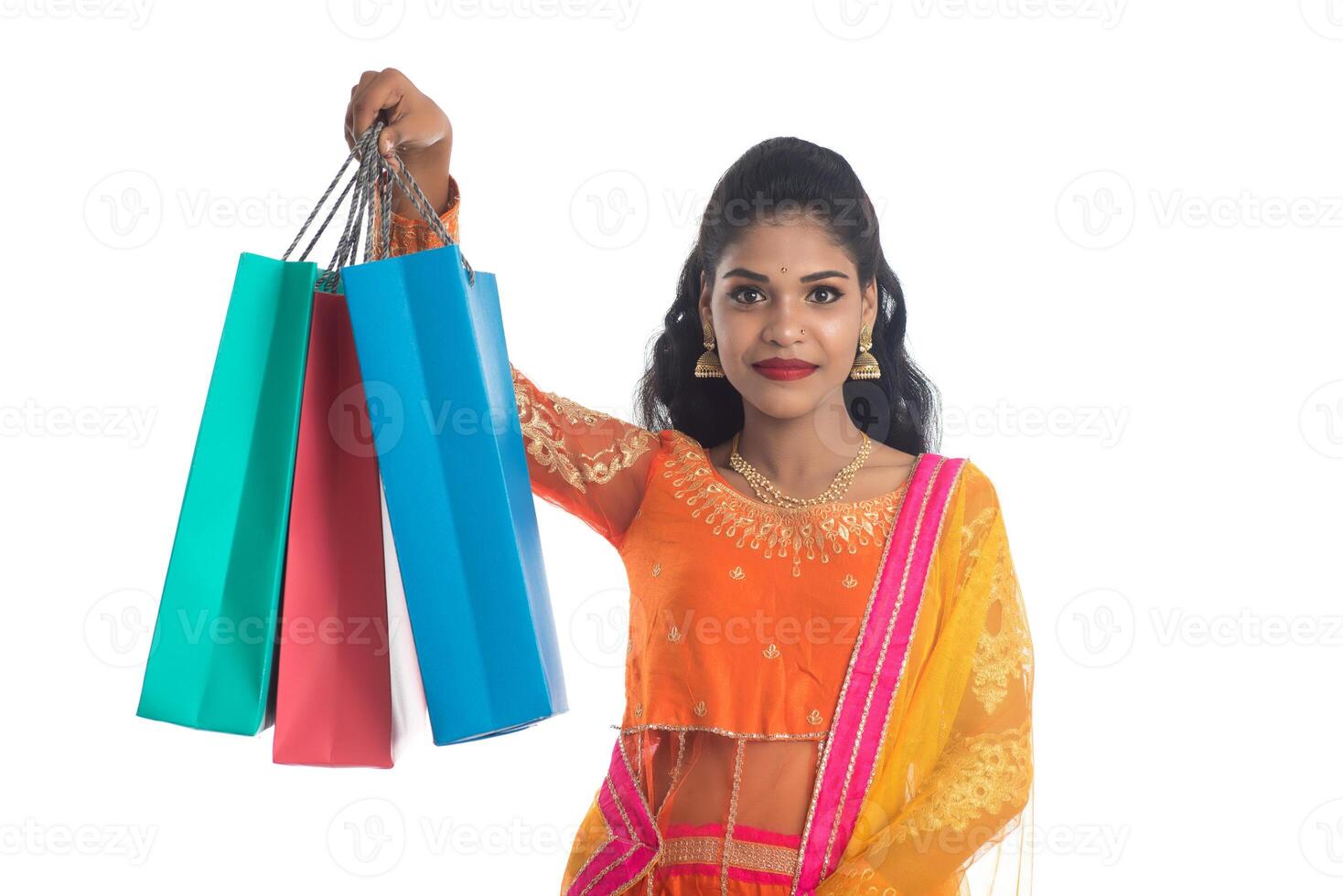 Beautiful Indian young girl holding shopping bags while wearing traditional ethnic wear. Isolated on a white background photo