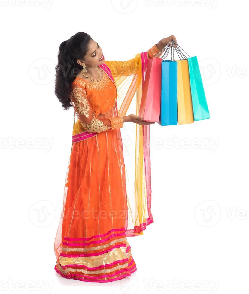 Beautiful Indian young girl holding shopping bags while wearing traditional ethnic wear. Isolated on a white background photo