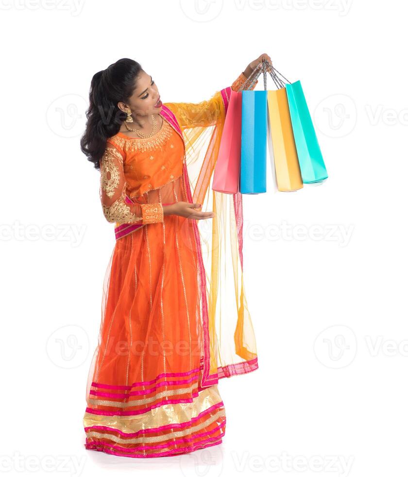 Beautiful Indian young girl holding shopping bags while wearing traditional ethnic wear. Isolated on a white background photo