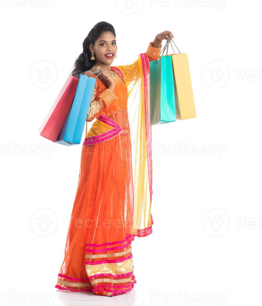 Beautiful Indian young girl holding shopping bags while wearing traditional ethnic wear. Isolated on a white background photo