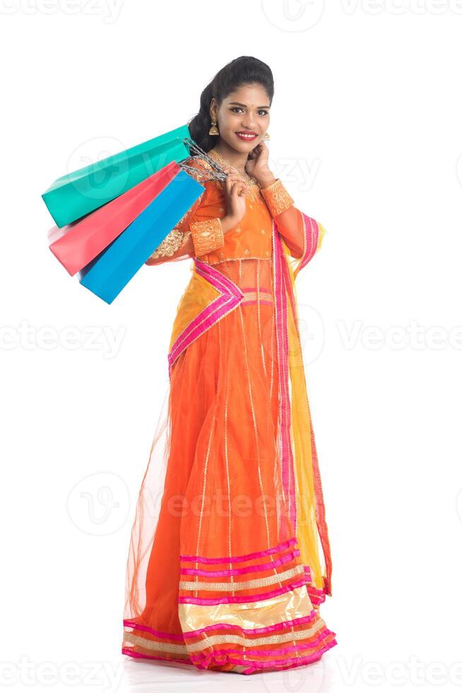 Beautiful Indian young girl holding shopping bags while wearing traditional ethnic wear. Isolated on a white background photo