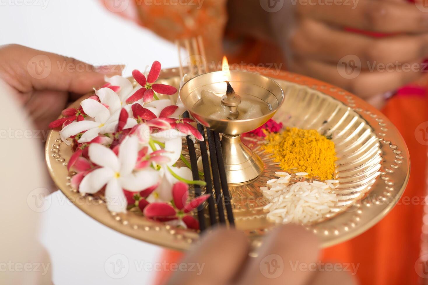 Beautiful Indian young girl holding pooja thali or performing worship on a white background photo