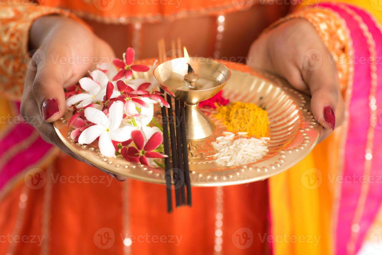 Beautiful Indian young girl holding pooja thali or performing worship on a white background photo