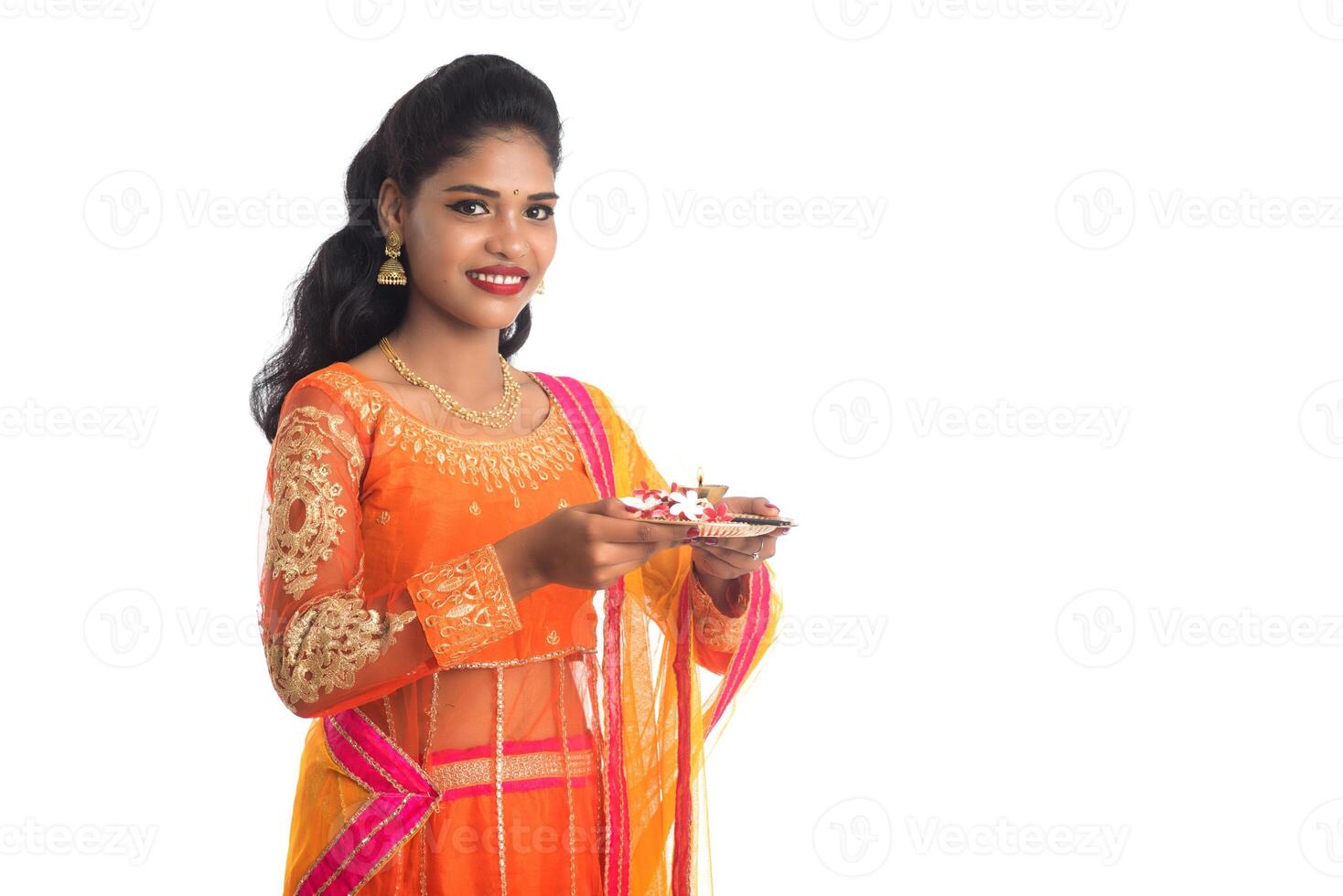 Beautiful Indian young girl holding pooja thali or performing worship on a white background photo