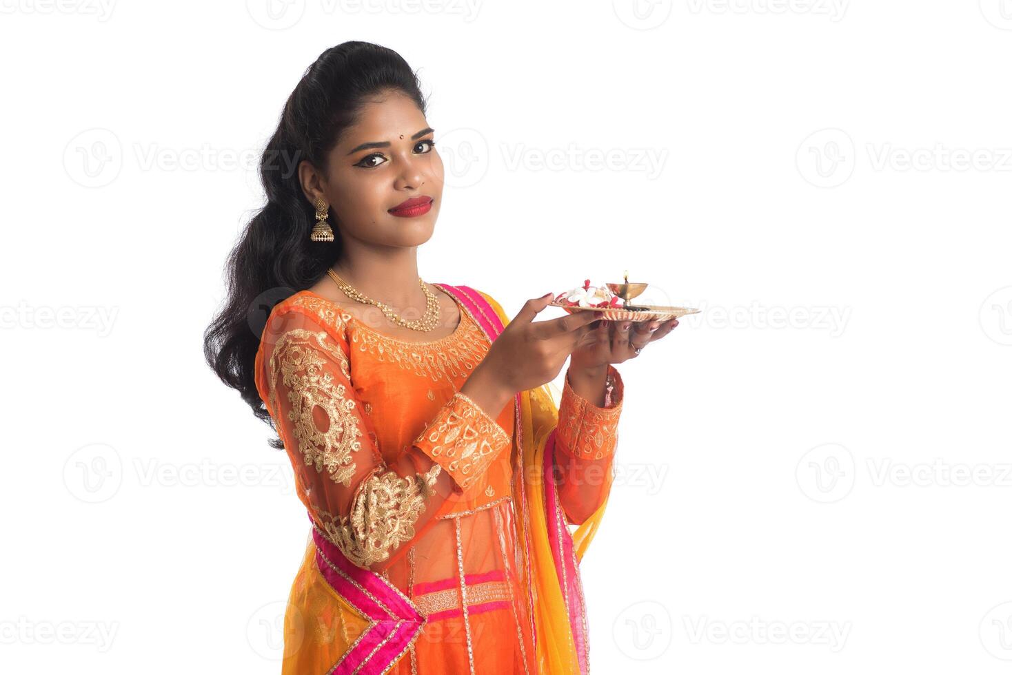 Beautiful Indian young girl holding pooja thali or performing worship on a white background photo