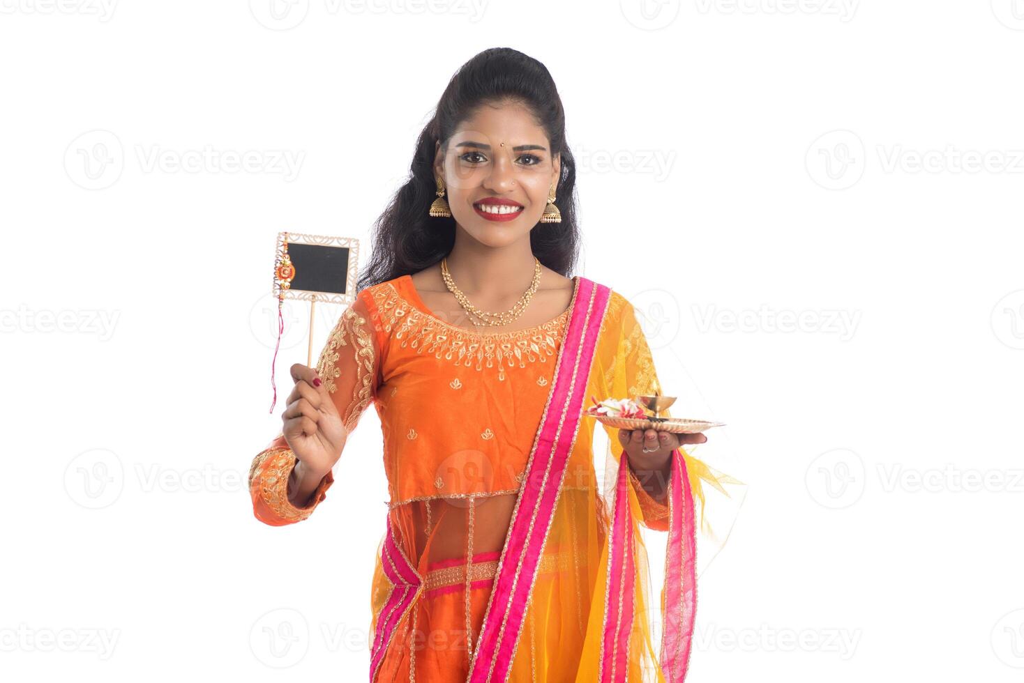 Beautiful Indian girl showing Rakhi on occasion of Raksha Bandhan with pooja thali and black board. Sister tie Rakhi as a symbol of intense love for her brother. photo