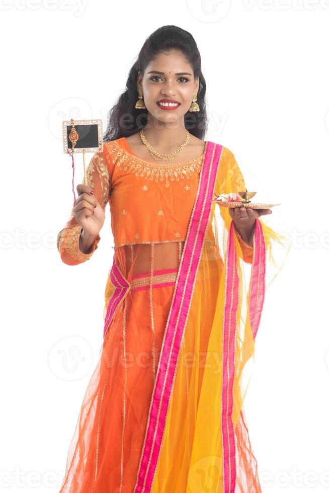 Beautiful Indian girl showing Rakhi on occasion of Raksha Bandhan with pooja thali and black board. Sister tie Rakhi as a symbol of intense love for her brother. photo