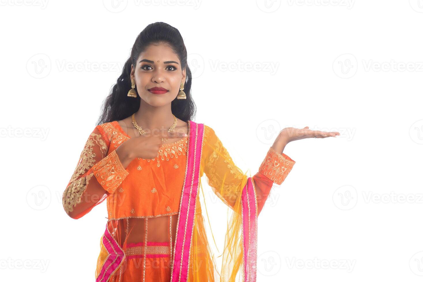 Portrait of cheerful Indian traditional young woman presenting something on hand, showing copy space on her palm on a white background photo