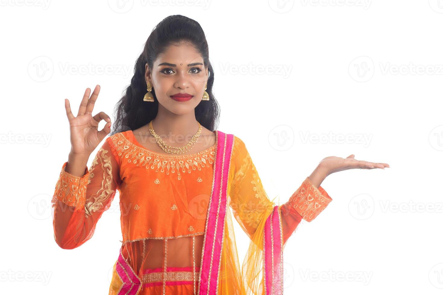 Portrait of cheerful Indian traditional young woman presenting something on hand, showing copy space on her palm on a white background photo