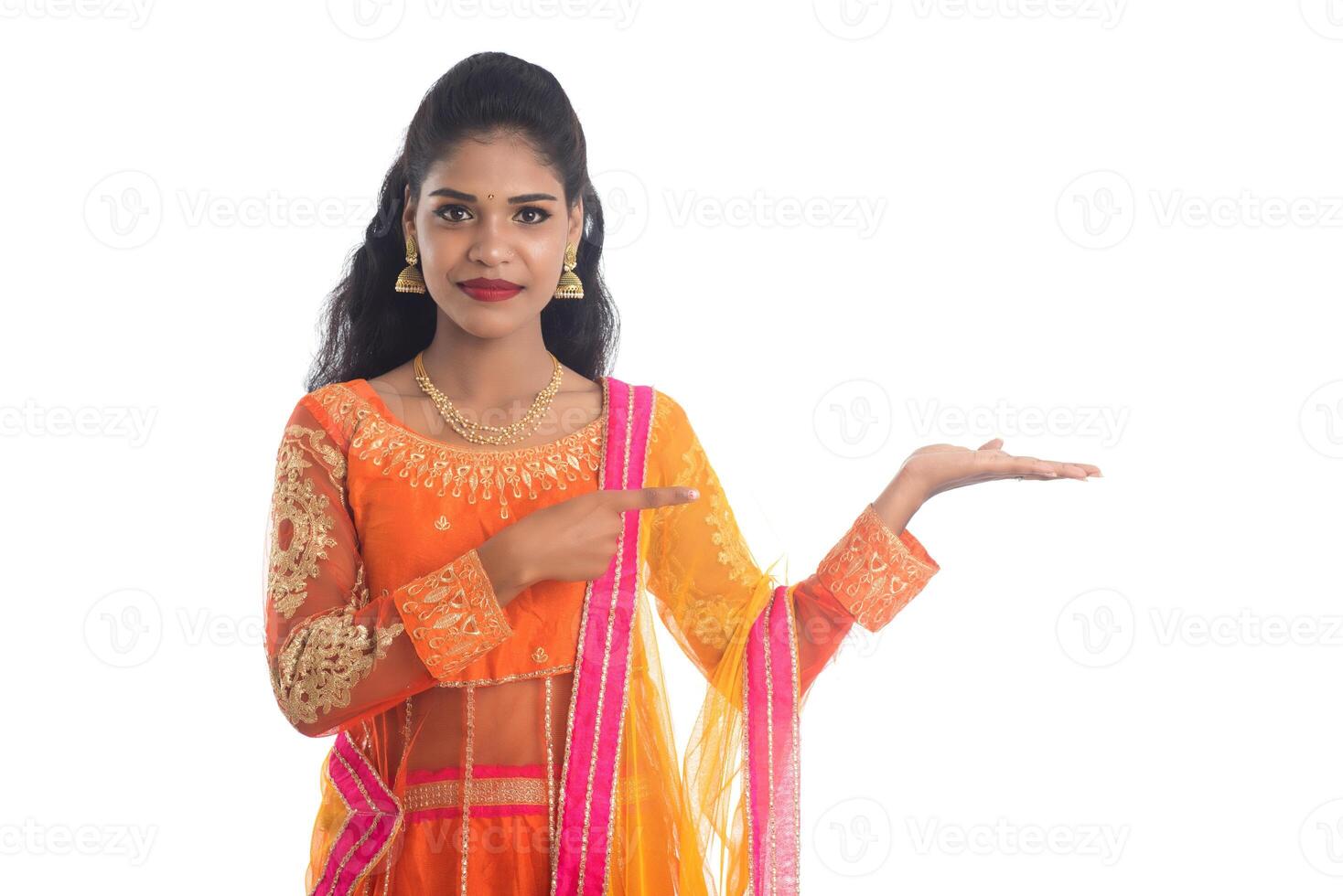 Portrait of cheerful Indian traditional young woman presenting something on hand, showing copy space on her palm on a white background photo
