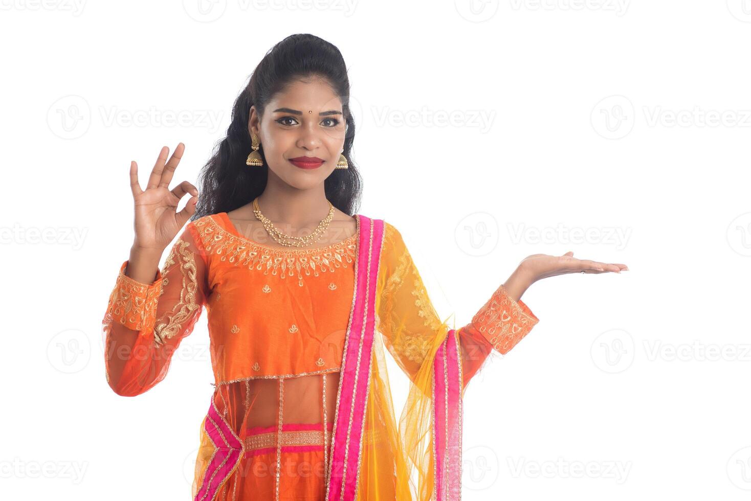 Portrait of cheerful Indian traditional young woman presenting something on hand, showing copy space on her palm on a white background photo