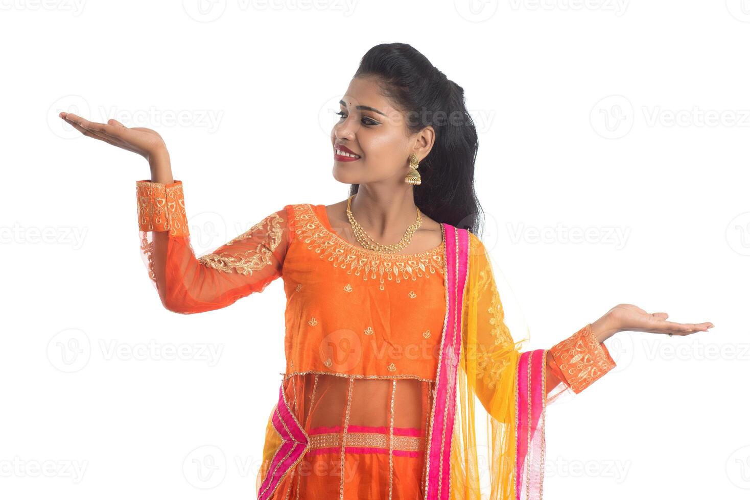 Portrait of cheerful Indian traditional young woman presenting something on hand, showing copy space on her palm on a white background photo