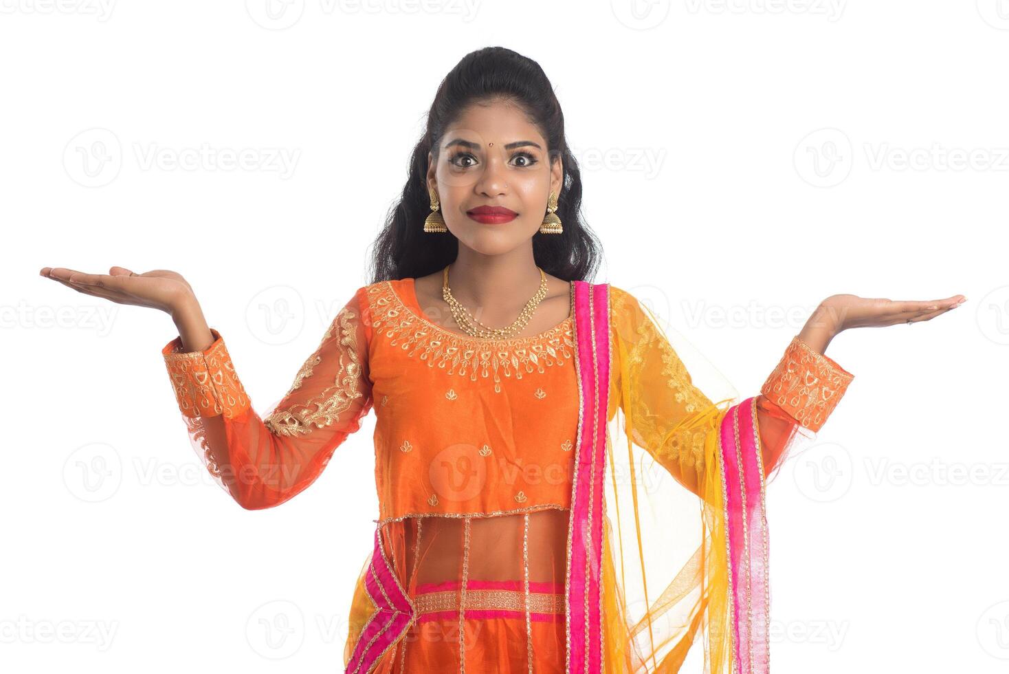 Portrait of cheerful Indian traditional young woman presenting something on hand, showing copy space on her palm on a white background photo