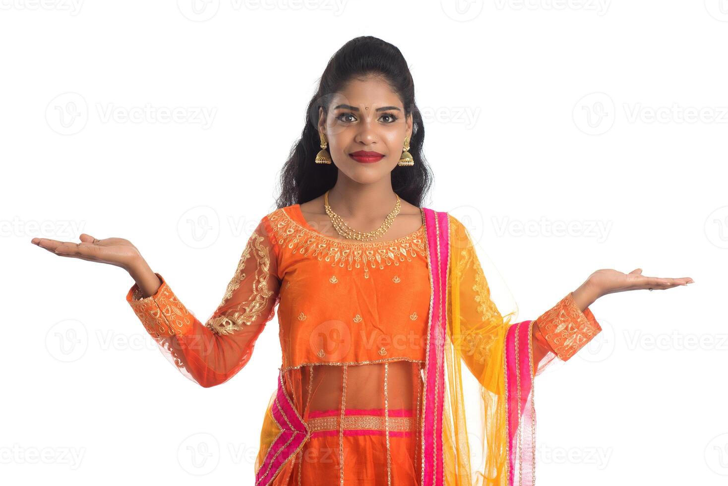 Portrait of cheerful Indian traditional young woman presenting something on hand, showing copy space on her palm on a white background photo