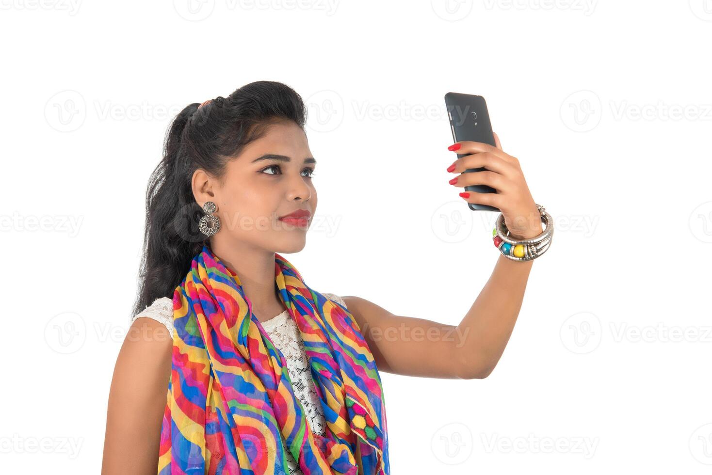 Young Indian girl using a mobile phone or smartphone isolated on a white background photo