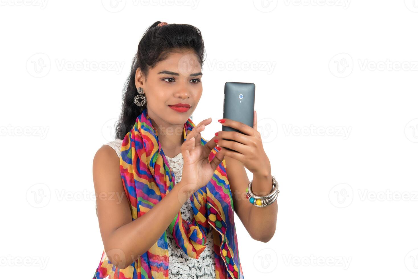 Young Indian girl using a mobile phone or smartphone isolated on a white background photo