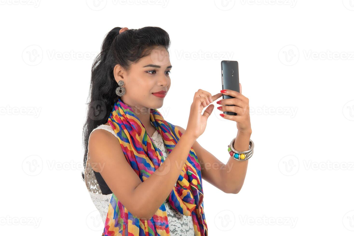 Young Indian girl using a mobile phone or smartphone isolated on a white background photo
