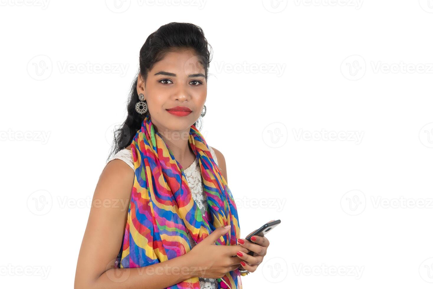 Young Indian girl using a mobile phone or smartphone isolated on a white background photo