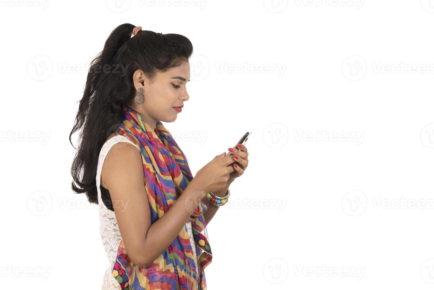 Young Indian girl using a mobile phone or smartphone isolated on a white background photo