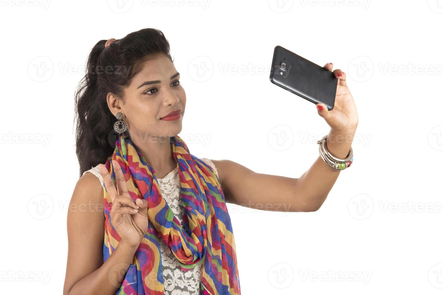 Young Indian girl using a mobile phone or smartphone isolated on a white background photo