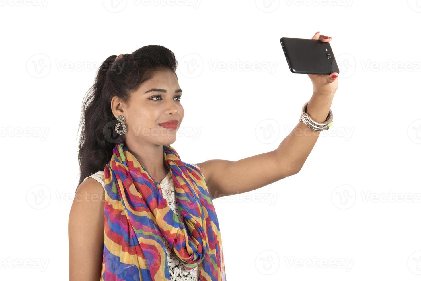 Young Indian girl using a mobile phone or smartphone isolated on a white background photo