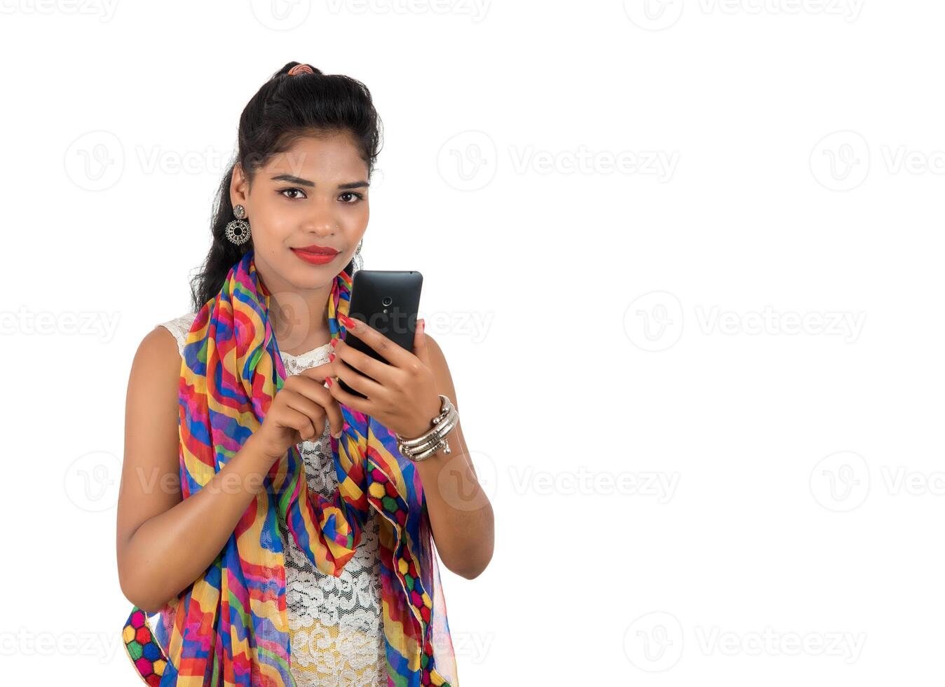 Young Indian girl using a mobile phone or smartphone isolated on a white background photo