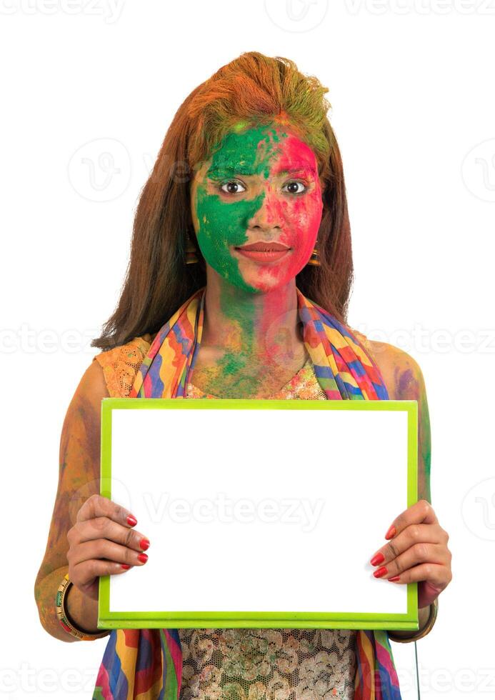 Girl holding a white signboard with face painted with color in Festival of Colour Holi. Isolated portrait photo