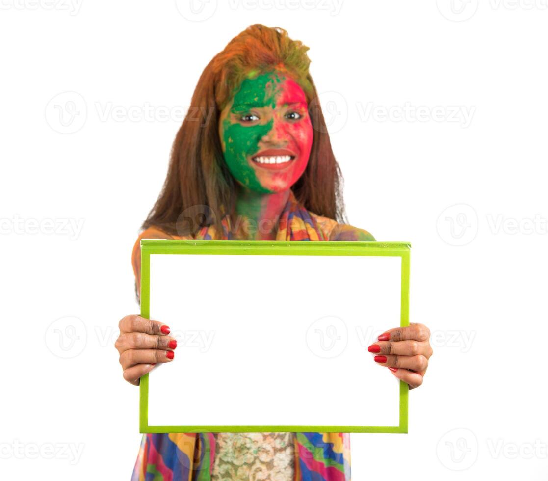 Girl holding a white signboard with face painted with color in Festival of Colour Holi. Isolated portrait photo