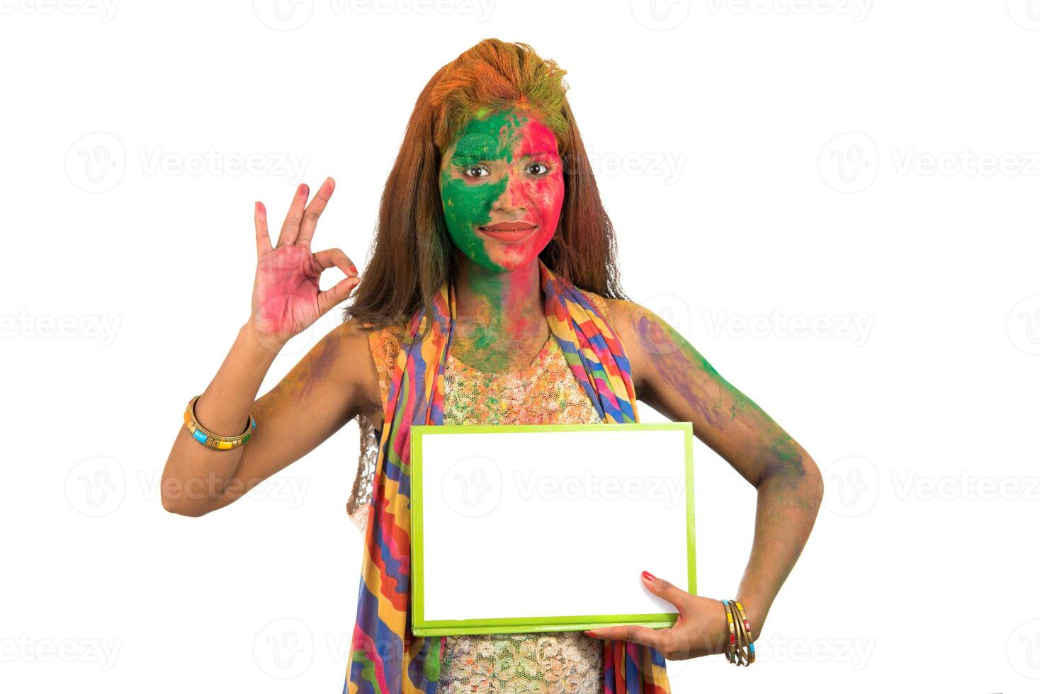 Girl holding a white signboard with face painted with color in Festival of Colour Holi. Isolated portrait photo