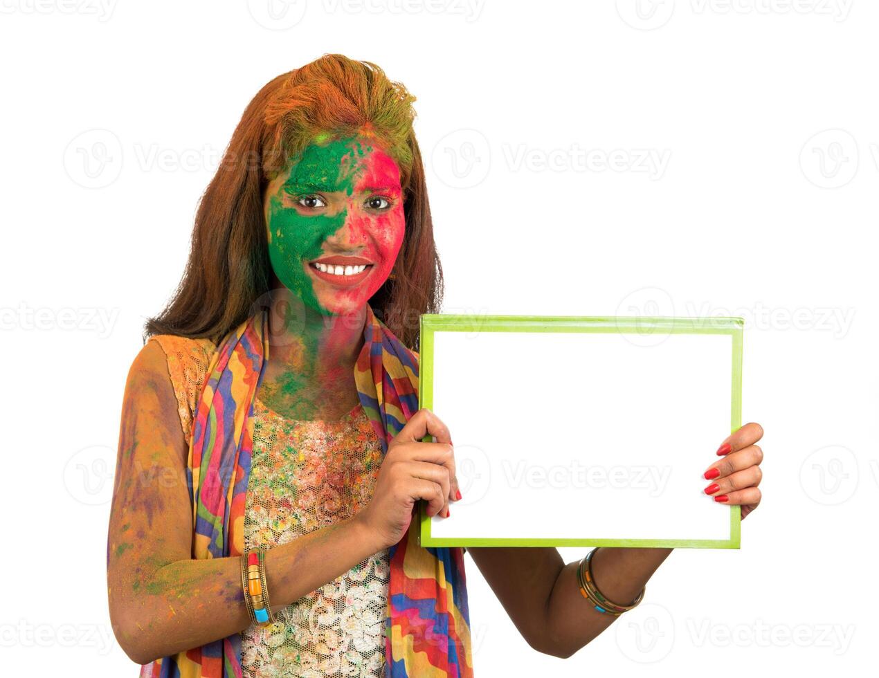 Girl holding a white signboard with face painted with color in Festival of Colour Holi. Isolated portrait photo