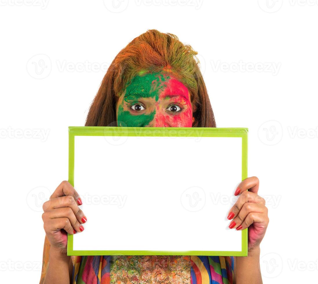 Girl holding a white signboard with face painted with color in Festival of Colour Holi. Isolated portrait photo