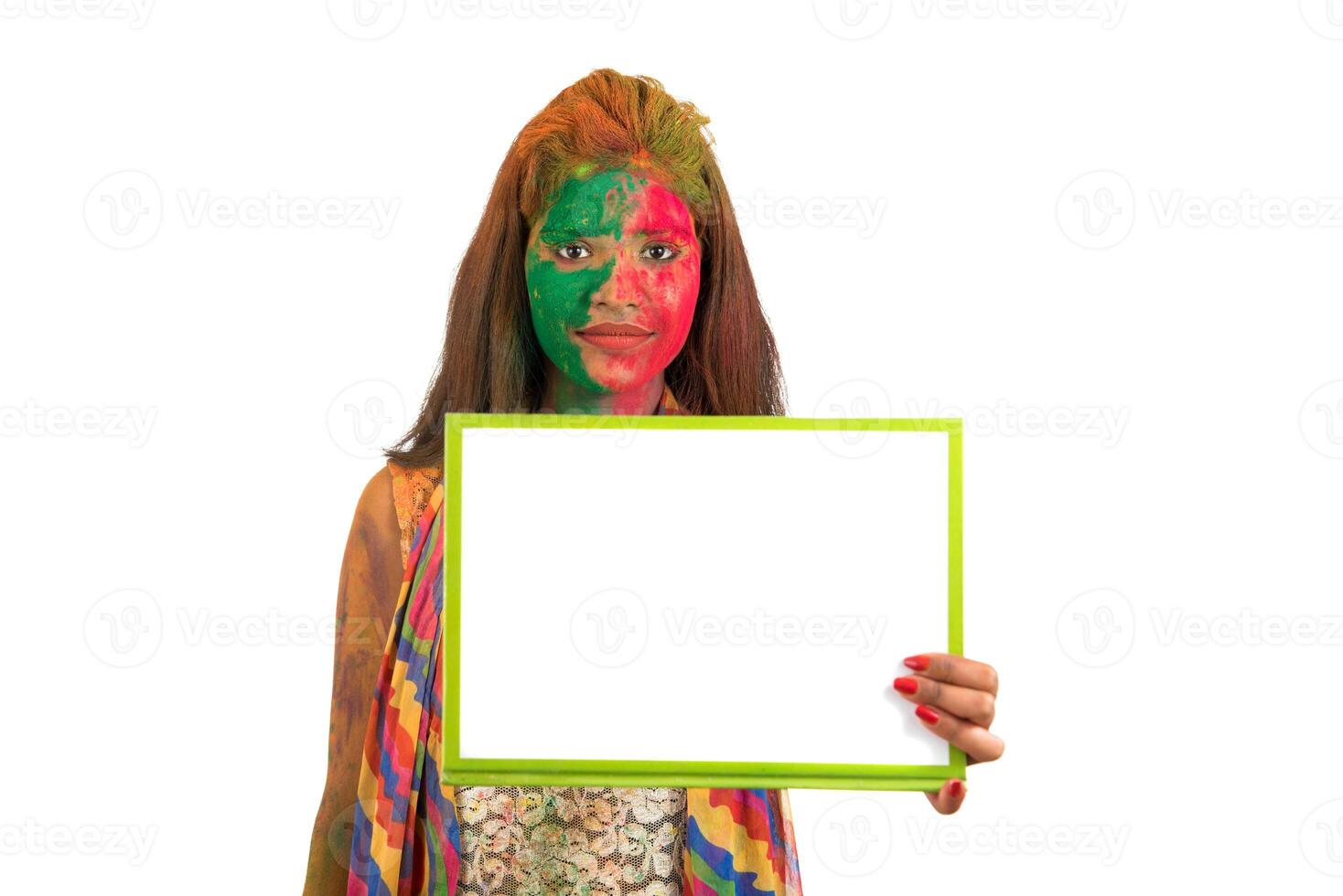 Girl holding a white signboard with face painted with color in Festival of Colour Holi. Isolated portrait photo