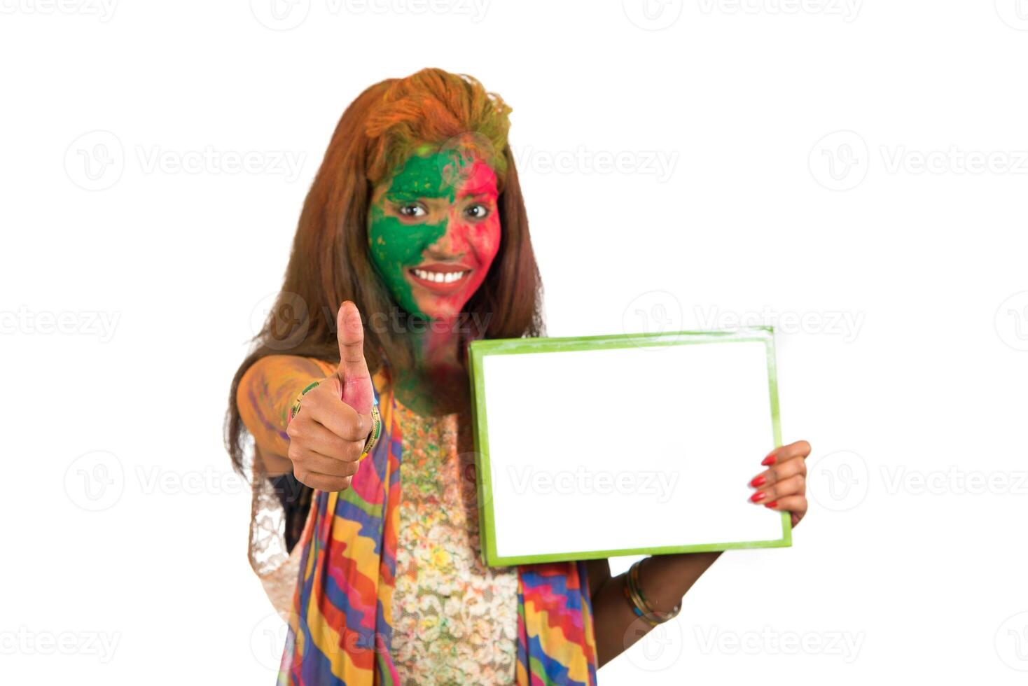Girl holding a white signboard with face painted with color in Festival of Colour Holi. Isolated portrait photo