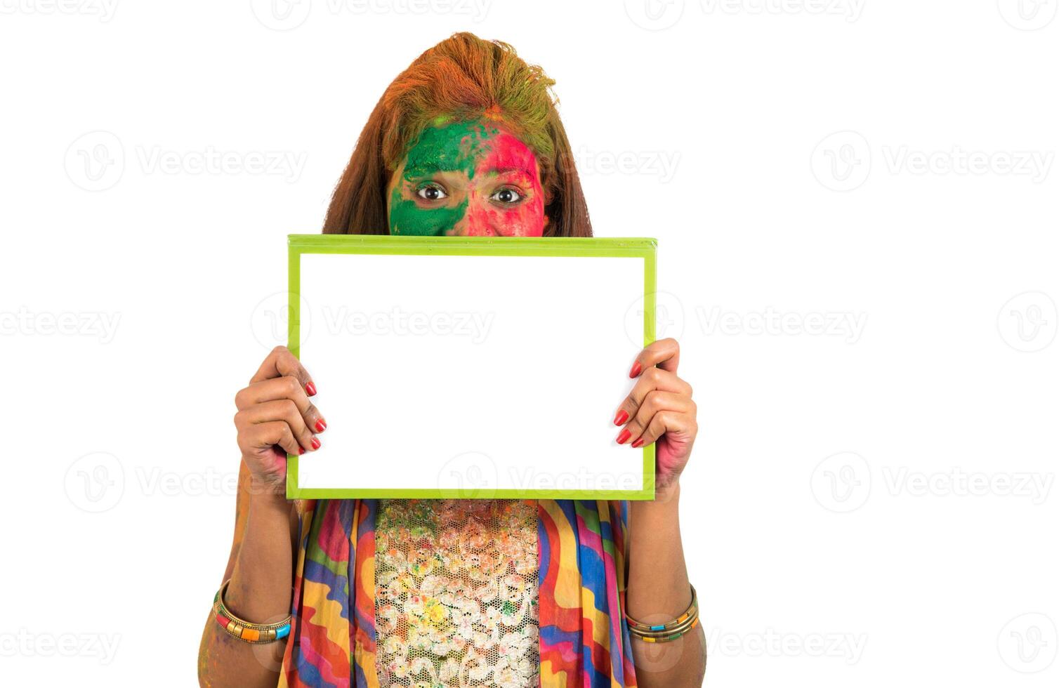 Girl holding a white signboard with face painted with color in Festival of Colour Holi. Isolated portrait photo