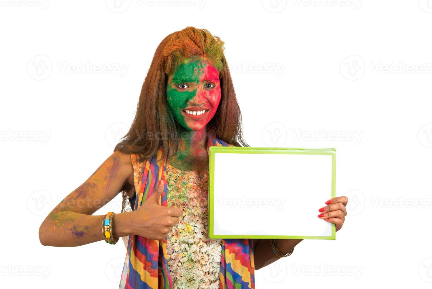 Girl holding a white signboard with face painted with color in Festival of Colour Holi. Isolated portrait photo