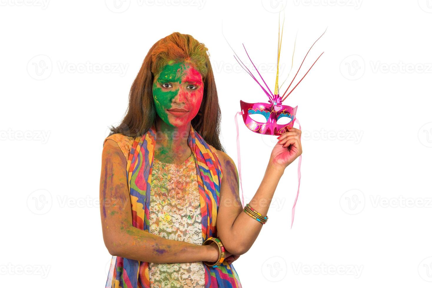 Girl with colorful face holding carnival mask and celebrating holi. photo