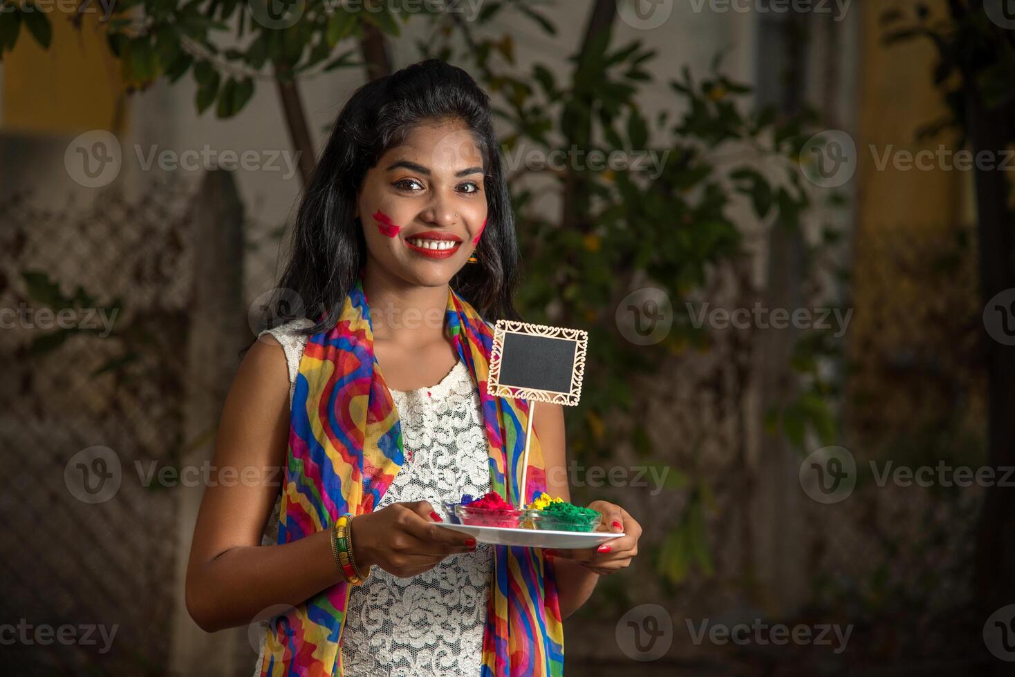 Young girl holding small board and powdered color on the occasion of Holi festival. photo