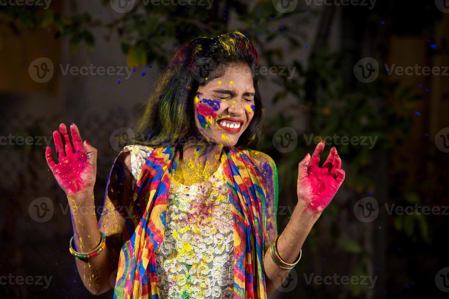 Young girl showing colorful palm and celebrating Holi with color splash photo