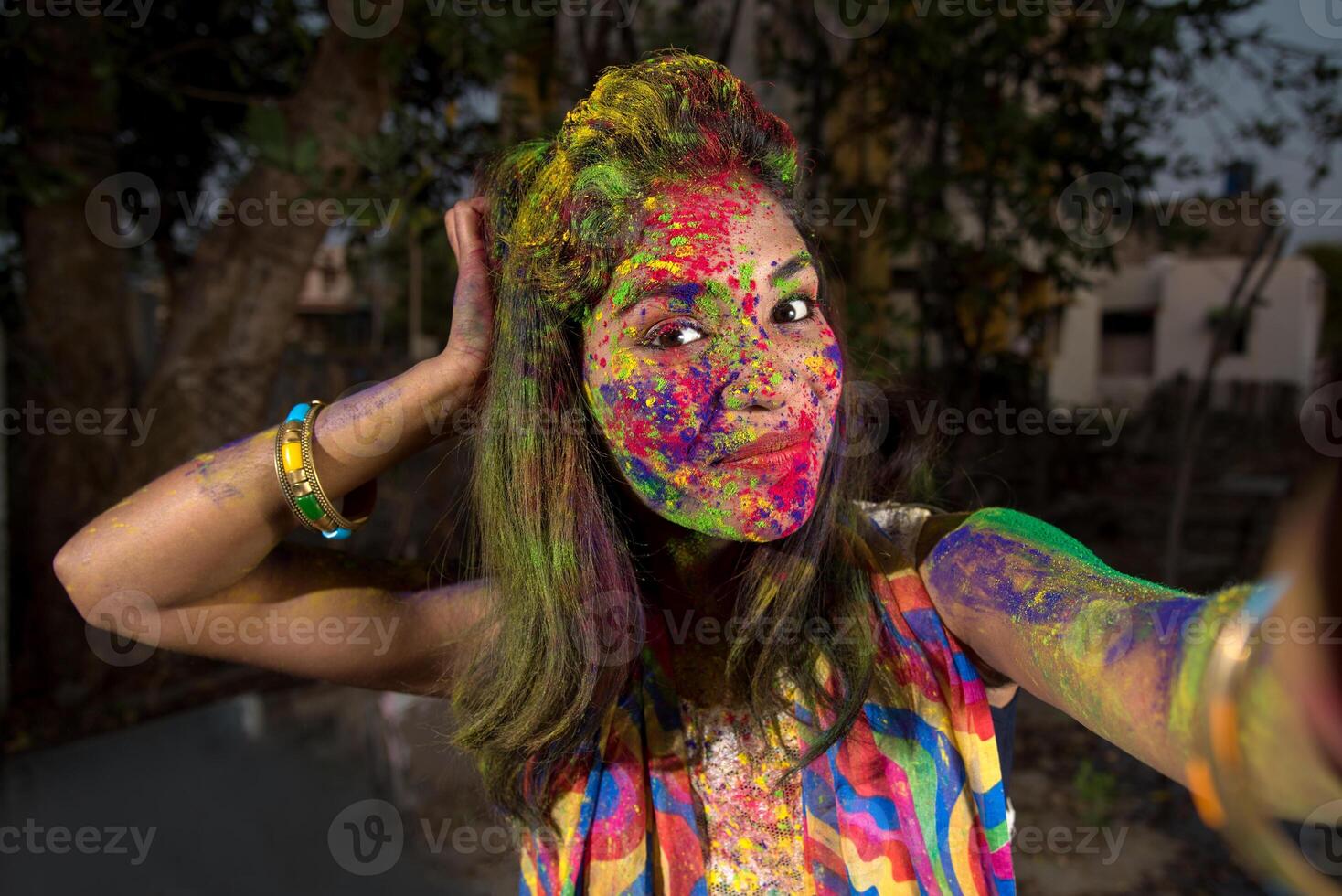 Young girl with colorful face taking selfie using smartphone on Holi festival. Festival and technology concept photo